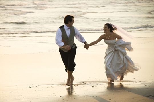 Bride and Groom running on beach